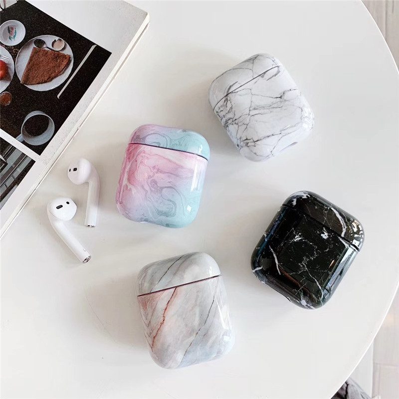 Elegant Marble AirPods Cases – Luxury White Marble AirPods Case Collection Luxury White Marble AirPods Case collection displayed on a white table with wireless earbuds and assorted marble designs.