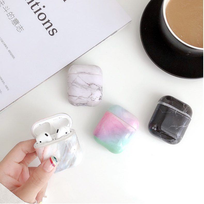 Lifestyle Display – Luxury White Marble AirPods Case Collection Luxury White Marble AirPods Case held in hand with three additional marble and pastel cases on white surface.
