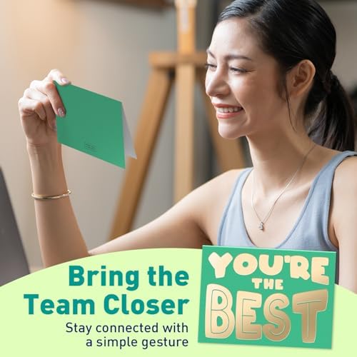 Employee Appreciation Cards for Coworkers – Strengthen Team Bonds with Simple Gestures Woman smiling while holding a green appreciation card that reads “YOU’RE THE BEST,” seated at a desk with a laptop, promoting team bonding and gratitude