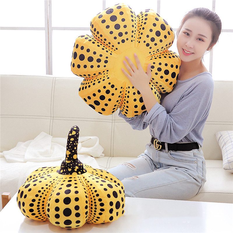 Pumpkin Plushies – Artistic Pairing Person holding a flower-shaped yellow plushie with a pumpkin plushie beside them on a couch