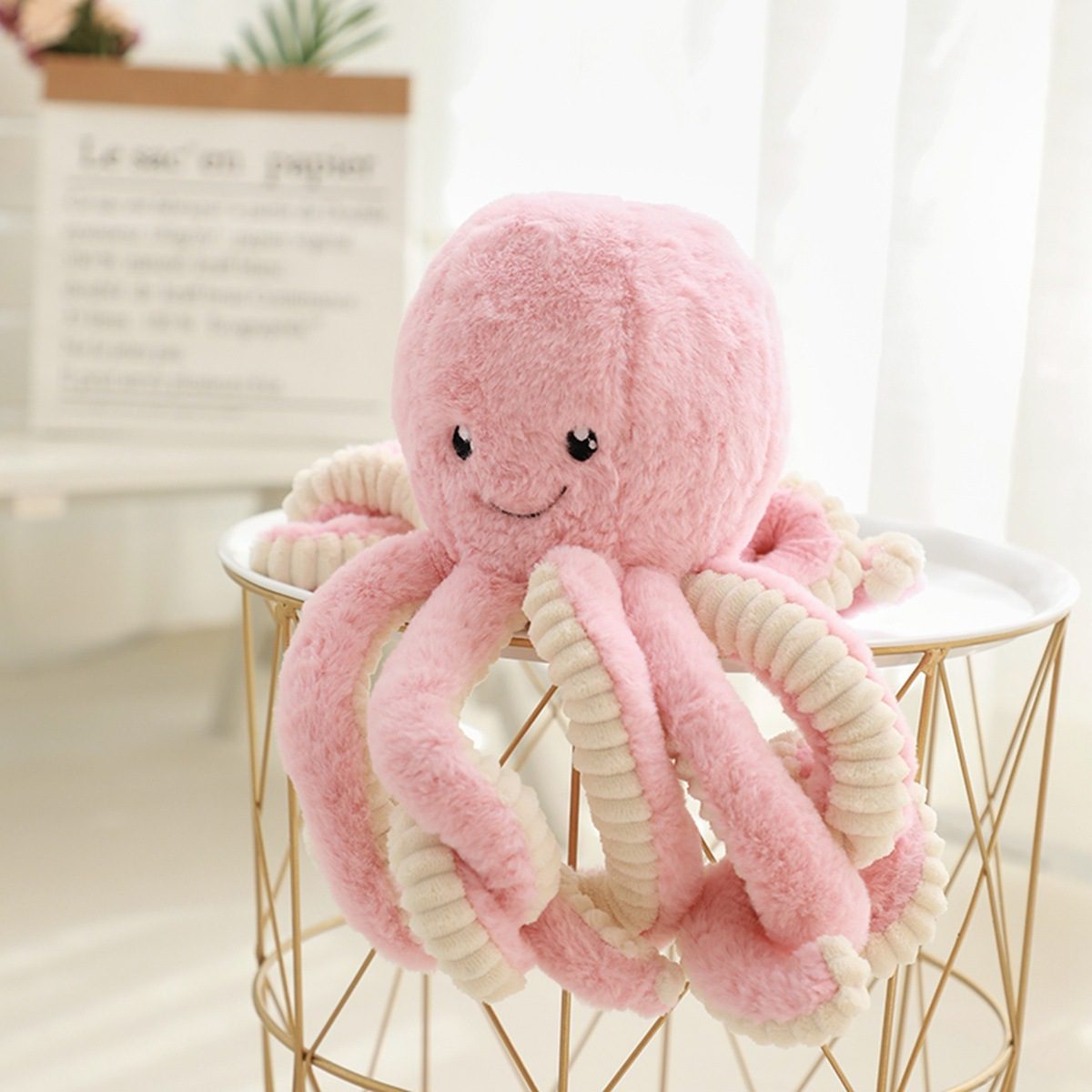 Octopus Stuffed Animal Plushie – Blush Bubble Friend Pink octopus stuffed animal plushie with cream-striped tentacles on a gold wire stool.