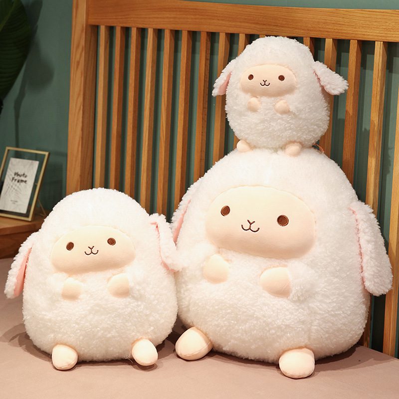 Round Sheep Plushie – Family Fleece Set Three round sheep plushies in different sizes arranged on a bed with wooden headboard.