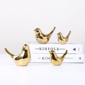 Four gold bird figurines placed on stacked books titled “THE KINFOLK HOME” and “THE KINFOLK ENTREPRENEUR.”