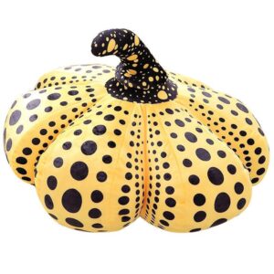 Large yellow pumpkin sculpture with black polka dots and a black stem.