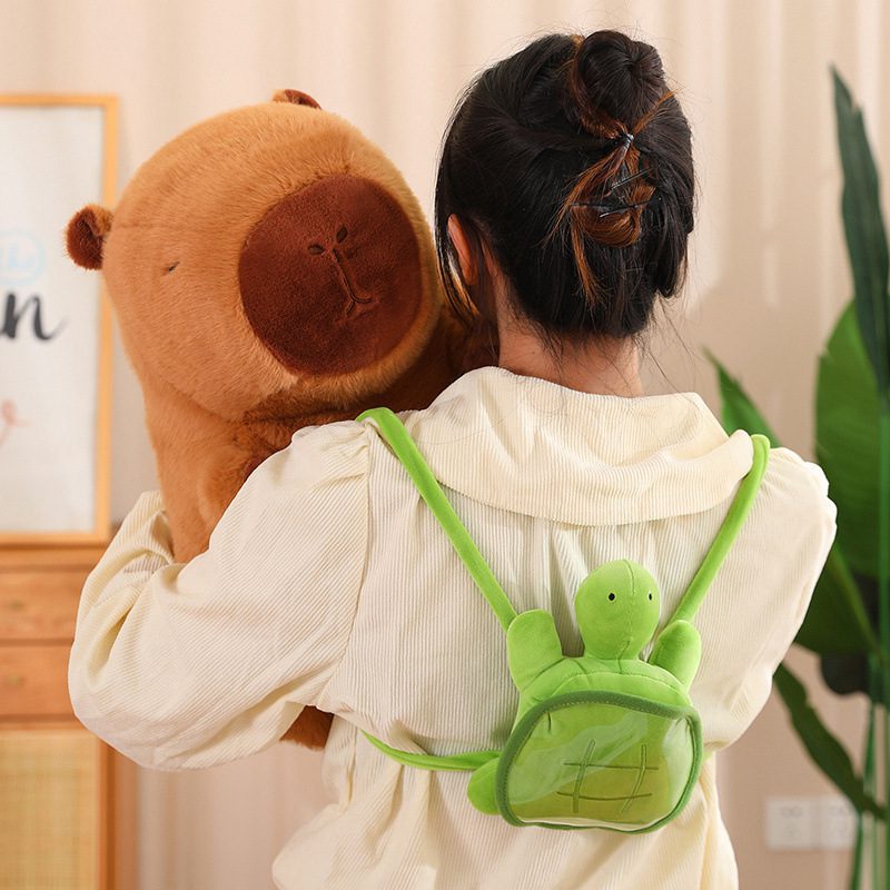 Capybara Plush Toy – Cozy Carry Edition Person wearing a turtle backpack and holding a large capybara plush toy, seen from behind.
